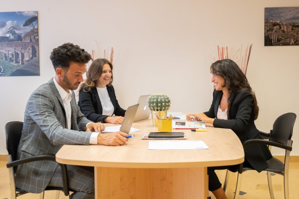 tre colleghi lavorano, chiacchierano e sorridono mentre lavorano nell'ufficio del majestic business center